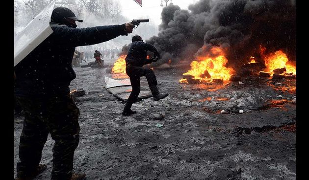 A protestor points a gun during clashes with riot police in the centre of Kiev on January 22, 2014. Ukrainian police today stormed protesters’ barricades in Kiev as violent clashes erupted and activists said that one person had been shot dead by the secur