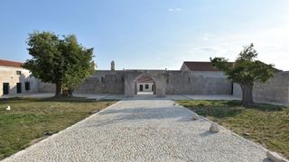 Han Maskovica izgradjen u 17. stoljecu i sluzio je u civilne svrhe kao svratiste, odmoriste i rezidencija. Objekt je izgradio Jusuf Maskovic, visoki dostojanstvenik na turskom dvoru, inace rodom iz Vrane ili iz Pakostana. Zapocet je u vrijeme izbijanja K Han Maskovica izgradjen u 17. stoljecu i sluzio je u civilne svrhe kao svratiste, odmoriste i rezidencija. Objekt je izgradio Jusuf Maskovic, visoki dostojanstvenik na turskom dvoru, inace rodom iz Vrane ili iz Pakostana. Zapocet je u vrijeme izbijanja K