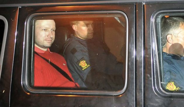 Bomb and terror suspect Anders Behring Breivik (red top) leaves the courthouse  in a police car  in Oslo on July 25, 2011, after the hearing to decide his further detention.  Breivik will be held in solitary confinement for the first four weeks, with a ba