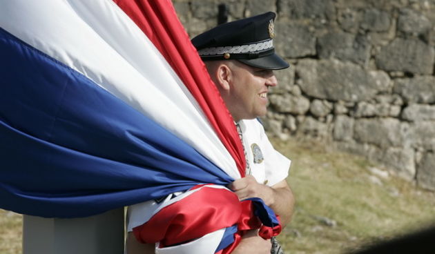 Knin, 050809.
U Kninu je obiljezena 14. obljetnica akcije Oluja
Policajac pridrzava zastavu da je ne odnese jak vjetar uoci podizanja na kninskoj tvrdjavi.
Foto: Jakov Prkic / Cropix