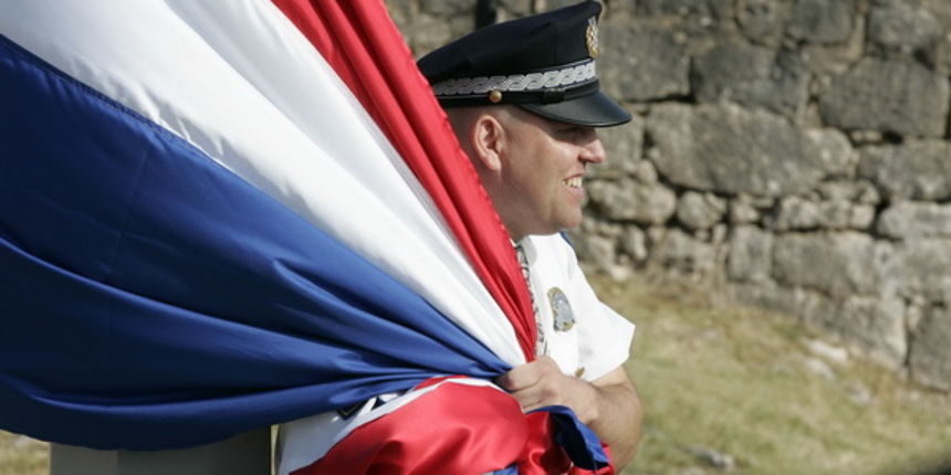 Knin, 050809.
U Kninu je obiljezena 14. obljetnica akcije Oluja
Policajac pridrzava zastavu da je ne odnese jak vjetar uoci podizanja na kninskoj tvrdjavi.
Foto: Jakov Prkic / Cropix