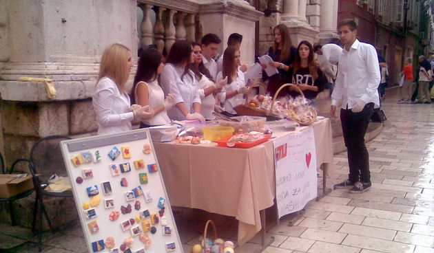 Oni su mladi i puni dobre volje – oni su zadarski volonteri koji su danas, unatoč lošem vremenu, postavili štand na Narodnom trgu kako bi pokrenuli akciju – humanitarnu prodaju slastica pod nazivom ”No cookie left behind”