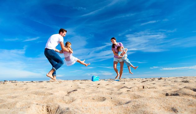 Mother and Father spinning their children round on the beach