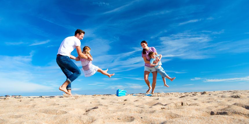 Mother and Father spinning their children round on the beach