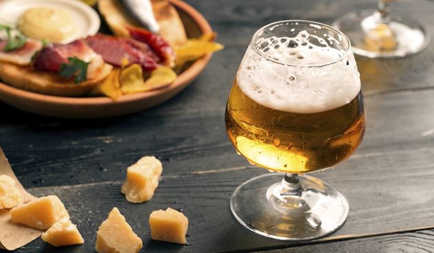 Two glasses of beer on the black table with snacks
