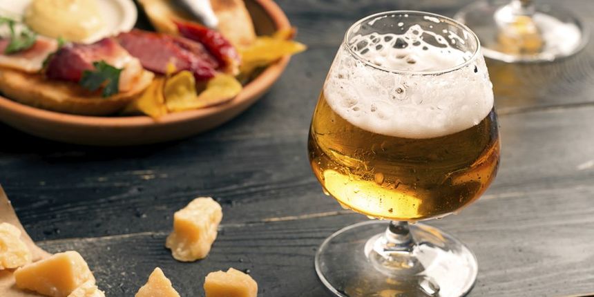 Two glasses of beer on the black table with snacks Two glasses of beer on the black table with snacks