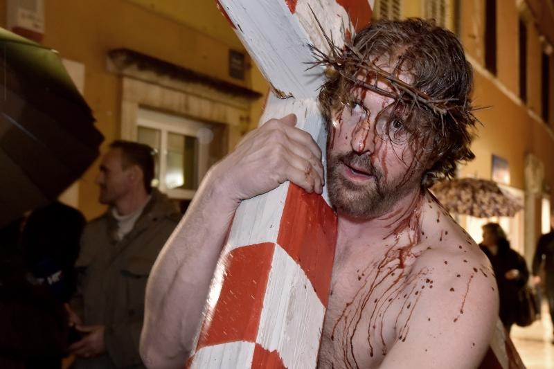 Zadarski performer Enio Mestrovic prosetao je centrom grada prerusen u Isusa noseci drveni kriz u hrvatskim detaljima. Prolazeci gradom uzvikivao je “Oprosti im Boze, ne znaju sto cine ni jedni ni drugi”. Photo: Dino Stanin/PIXSELL Zadarski performer Enio Mestrovic prosetao je centrom grada prerusen u Isusa noseci drveni kriz u hrvatskim detaljima. Prolazeci gradom uzvikivao je “Oprosti im Boze, ne znaju sto cine ni jedni ni drugi”. Photo: Dino Stanin/PIXSELL