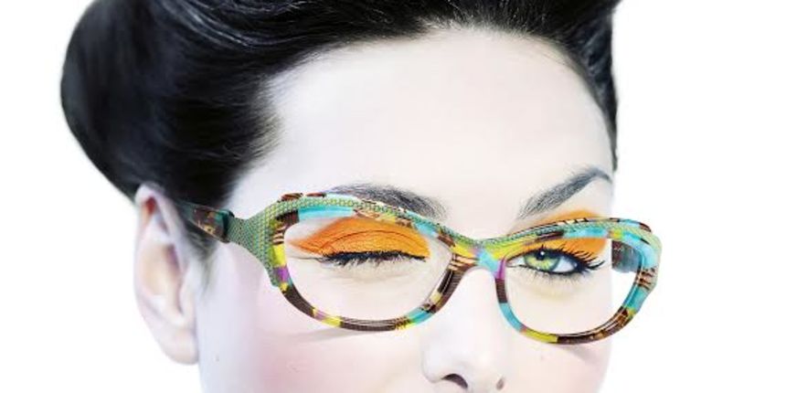 Model with fashionable hairstyle and orange eyeshadow winking.