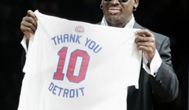 Former Detroit Piston Dennis Rodman holds up a t-short with his number 10 to thank the fans during a ceremony to retire his jersey at an NBA basketball game against the Chicago Bulls // AP Photo