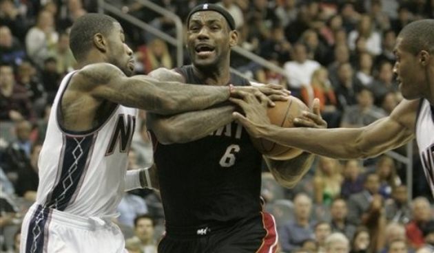 Miami Heat LeBron James fights off New Jersey Nets Terrence Williams and Derrick Favors // AP Photo