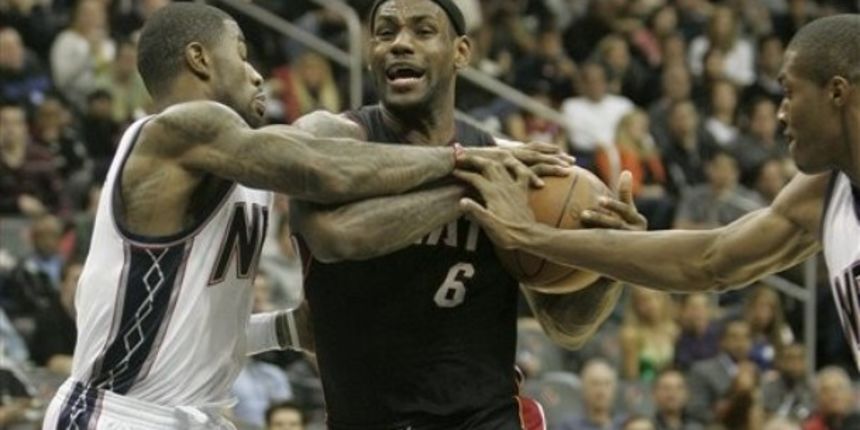 Miami Heat LeBron James fights off New Jersey Nets Terrence Williams and Derrick Favors // AP Photo