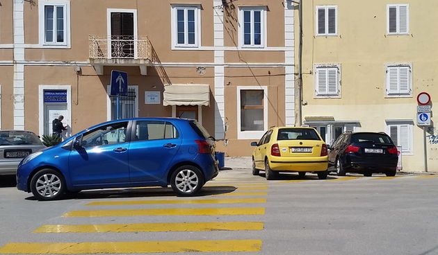 Tri automobila parkirana na zebri u ulici Stratico